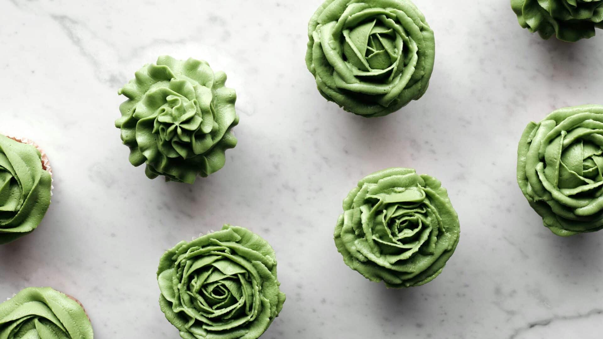 How to make flowers on top of cupcakes? with these beautiful green buttercream floral designs piped onto cupcakes on a marble surface.