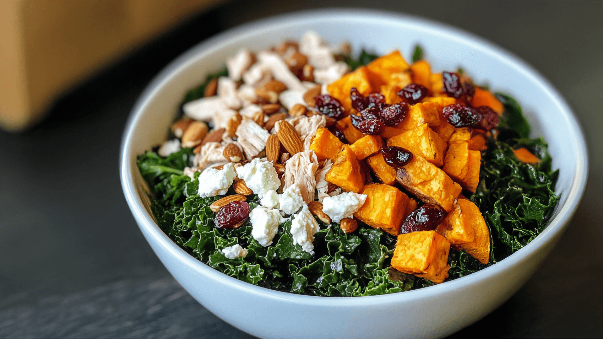 A vibrant and colorful Sweetgreen Harvest Bowl Recipe featuring kale, roasted sweet potatoes, cranberries, goat cheese, almonds, and shredded chicken.
