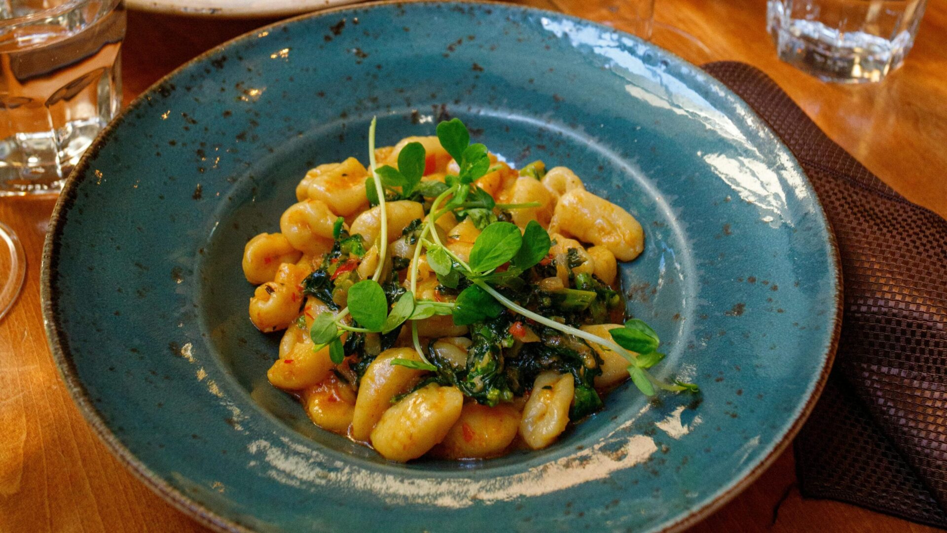 A plate of ditalini pasta served with a flavorful sauce, garnished with fresh greens.