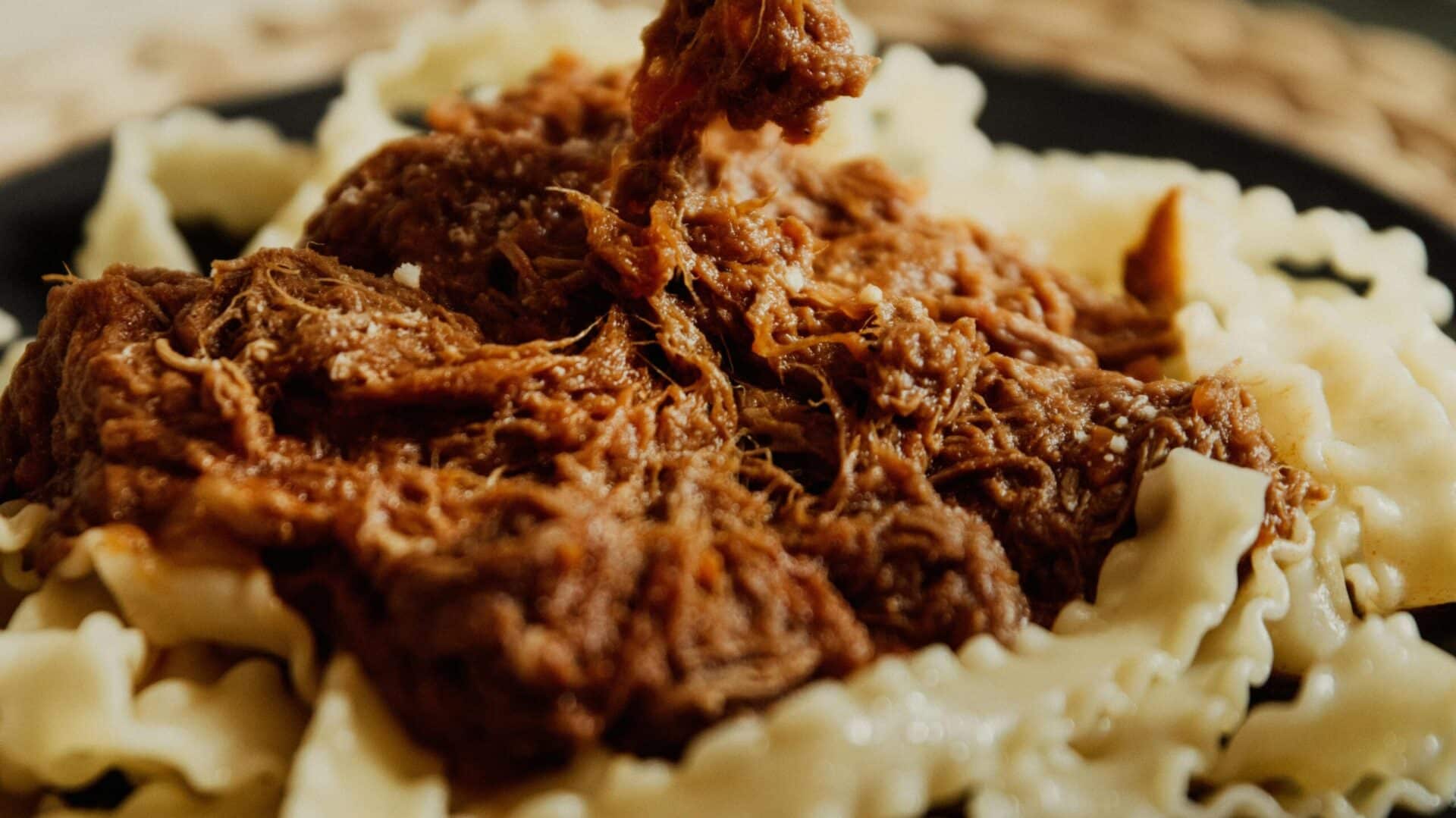 Close-up of Mafaldine pasta served with a rich, chunky meat sauce, showcasing its distinctive ribbon shape with ruffled edges.