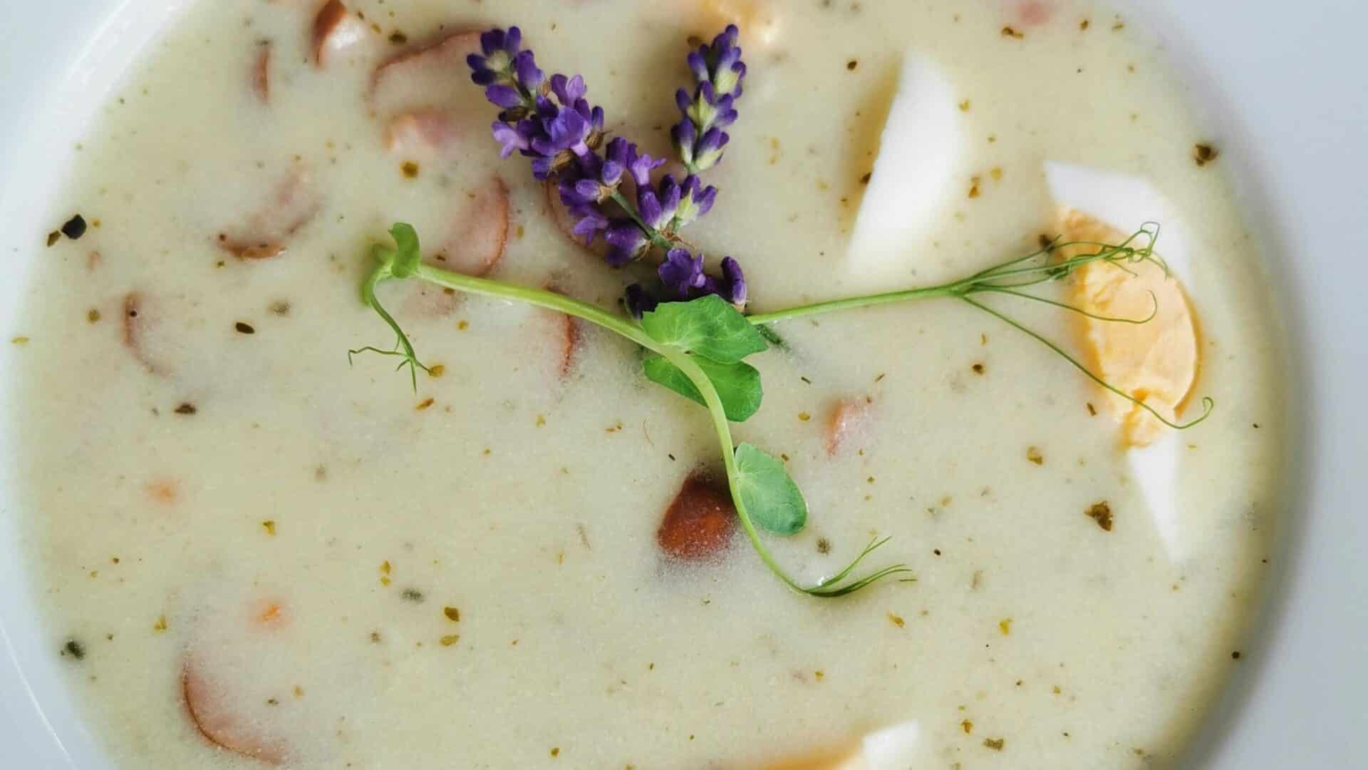 A bowl of creamy parmesan Italian sausage soup garnished with fresh herbs and hard-boiled eggs for an elegant presentation.