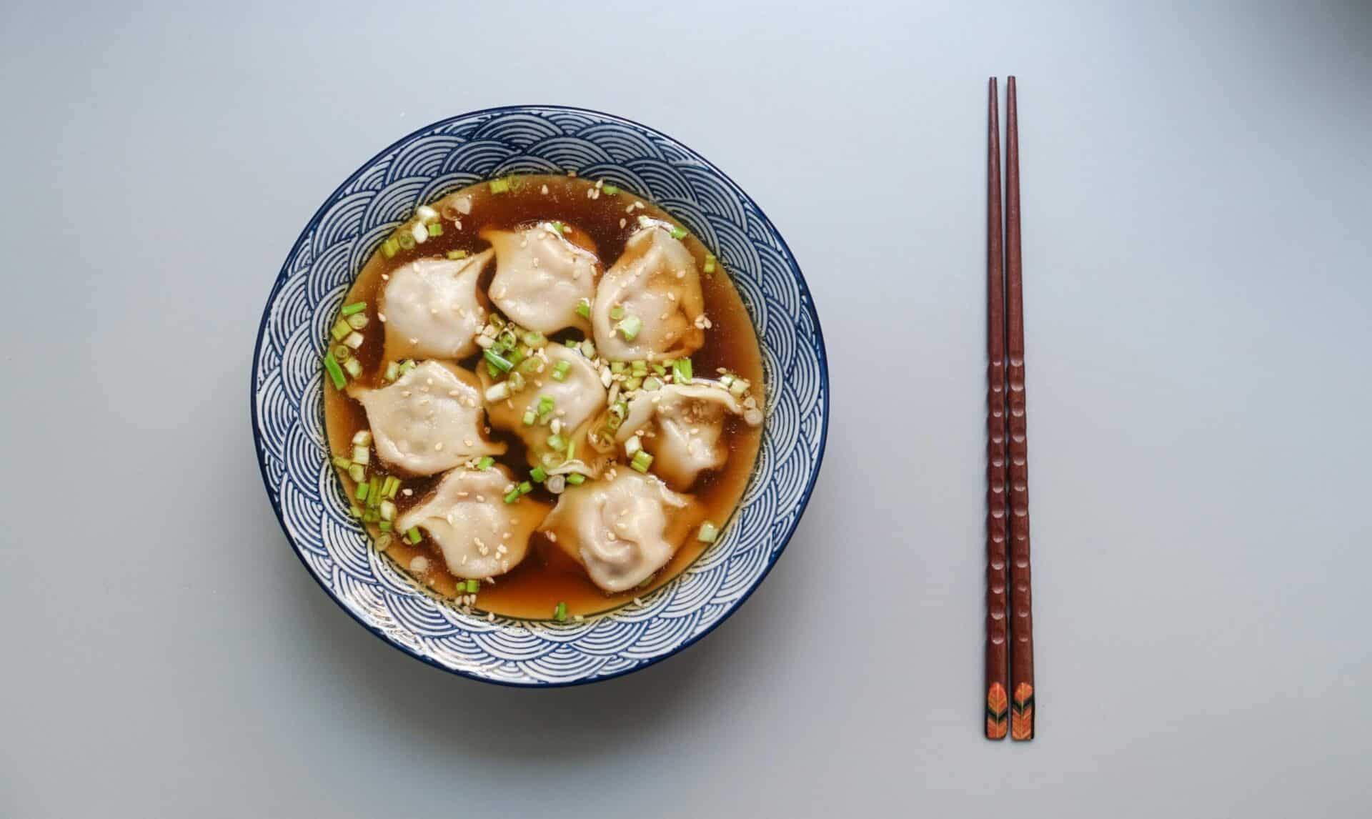 Vegan Soup Dumplings served in rich broth, garnished with fresh green onions and sesame seeds.