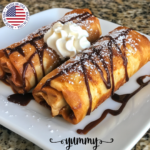 Close-up of Xango Dessert, featuring crispy fried cheesecake chimichangas topped with powdered sugar, chocolate drizzle, and whipped cream, served on a white plate.