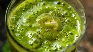 Home 5 Close-up of a Matcha Smoothie, featuring a creamy green texture, blended with banana, spinach, and almond milk, topped with matcha powder.