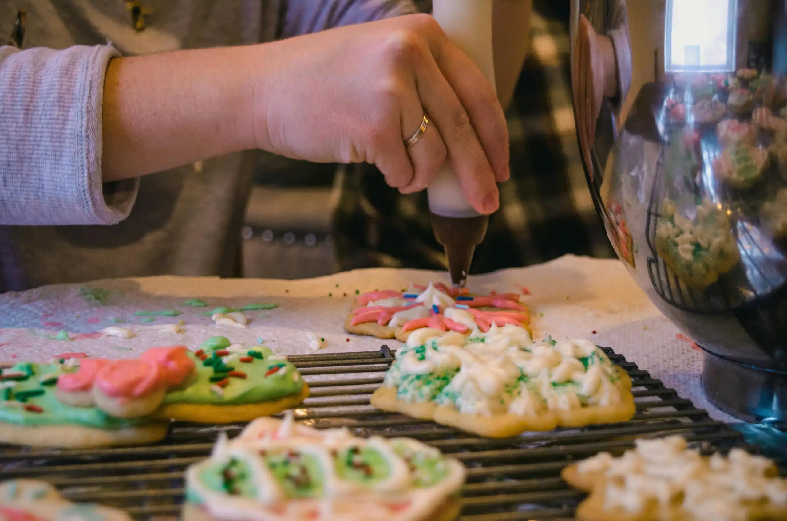 Close-up of Mery decorating cookies with icing and sprinkles, showcasing her creativity and baking skills.