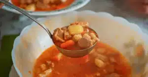 Home 2 Ladle filled with beef, potatoes, and vegetables from one of the best crockpot soup recipes.